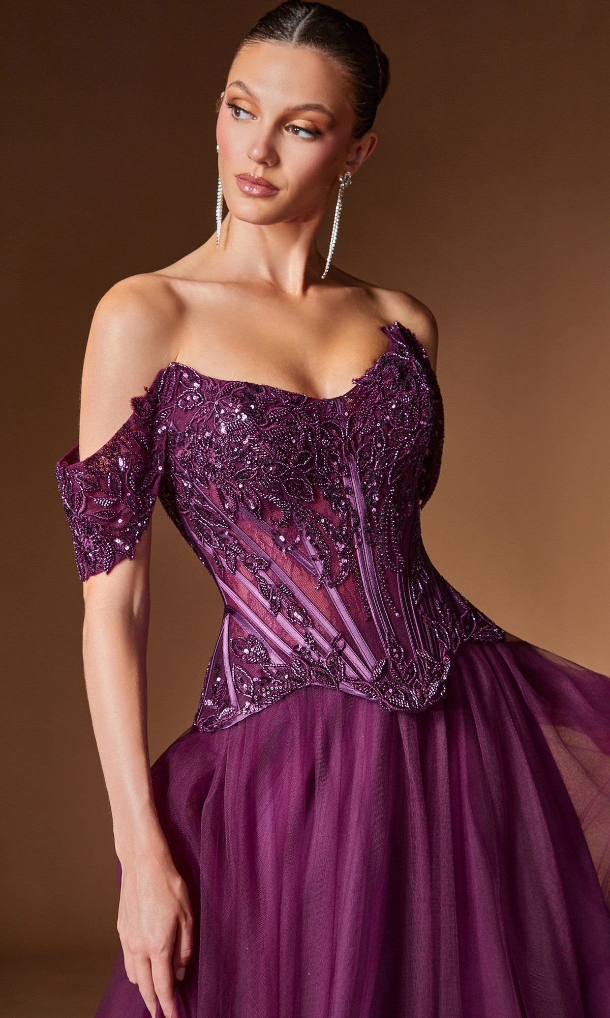 A woman poses against a brown background in the Ladivine CD657 long prom dress, featuring a deep purple off-shoulder design with a corset bodice, intricate beadwork, and a flowing tulle skirt.